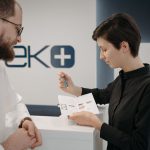 Customer discussing information sheet with receptionist in clinic.