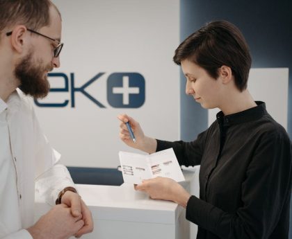 Customer discussing information sheet with receptionist in clinic.