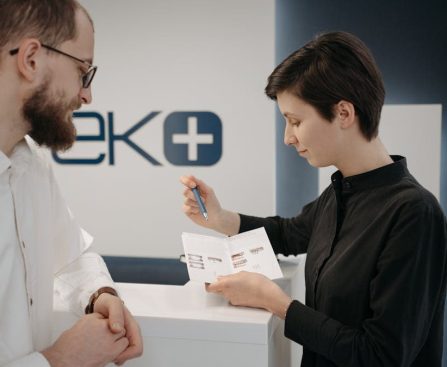 Customer discussing information sheet with receptionist in clinic.