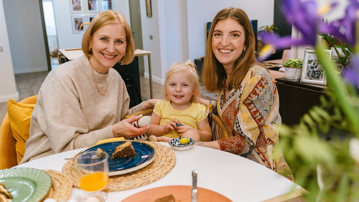 Three generations of smiling women enjoying a meal together indoors.